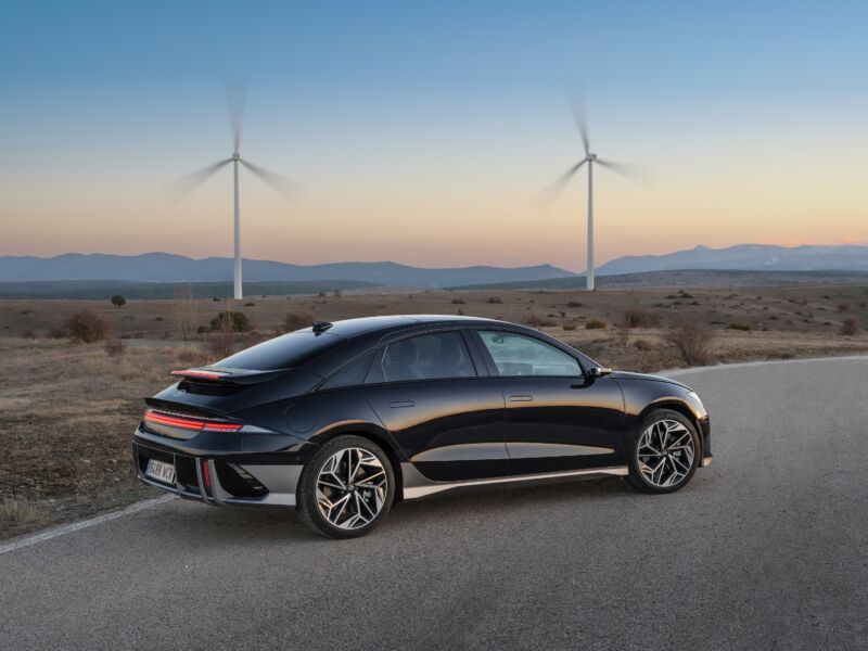 A black Hyundai Ioniq 6 with wind turbines in the background.